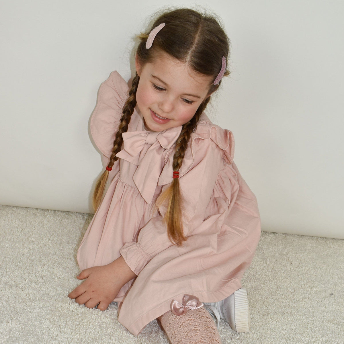 Meisje met twee vlechten en een beige en oudroze Teddy Candy haarspeldje aan weerszijden van haar scheiding.