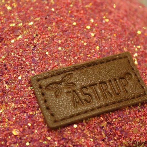 Detail van het roze glitterheuptasje met een bruin rechthoekig logolabel op de voorkant.