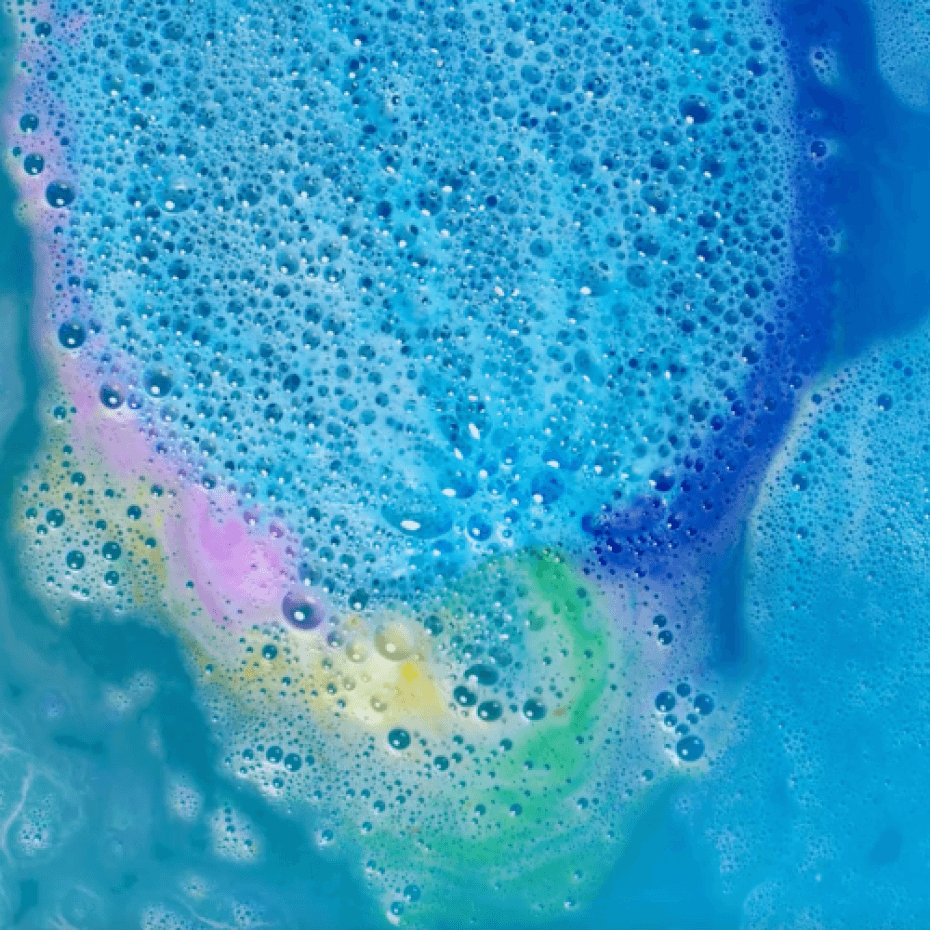 Blauw badwater met schuimende bubbels en roze, gele en groene kleurbanen van de regenboogbruisbal.