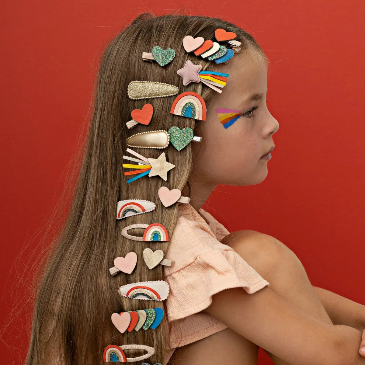 Meisje met Mimi & Lula-haarclips in de vorm van hartjes, sterren en regenbogen in haar lange haar.