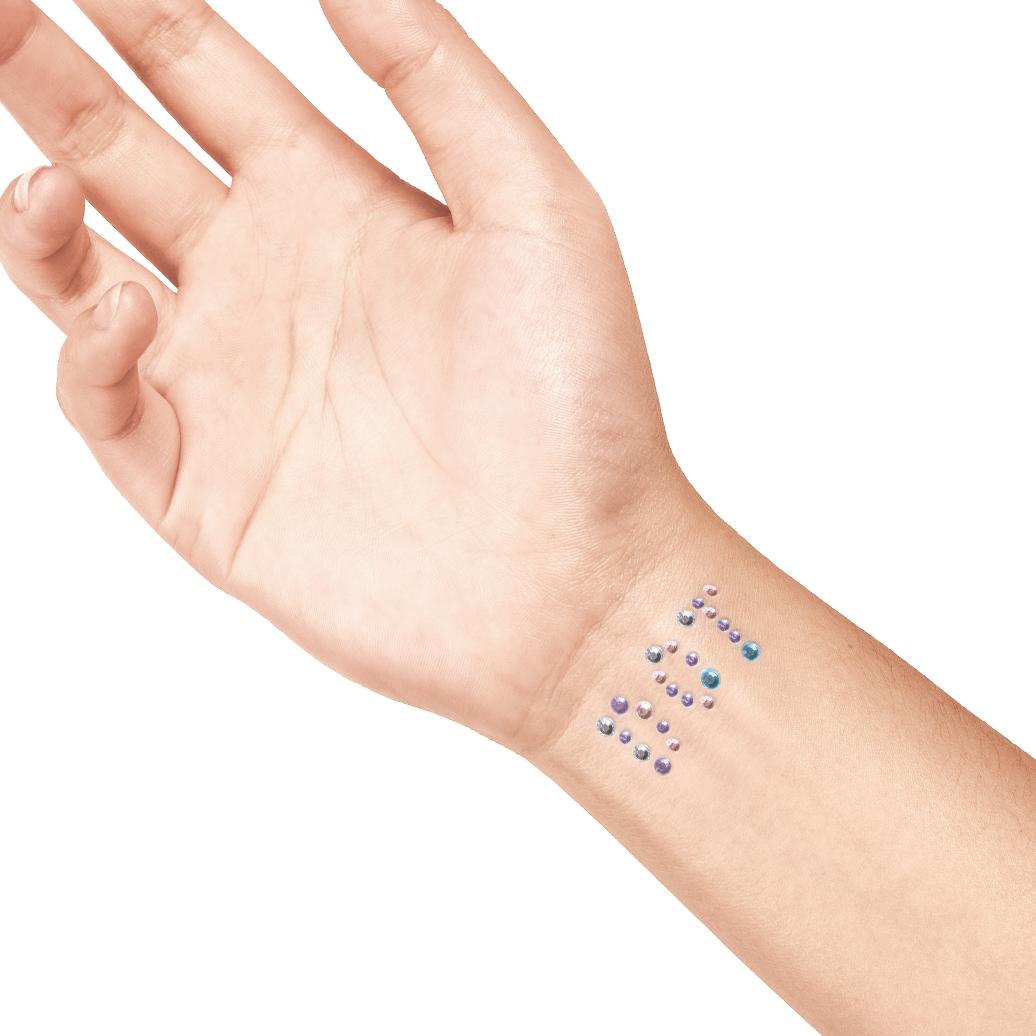 Roze, paarse en blauwe strass steentjes van La Dot in een sierlijk patroon op een pols.