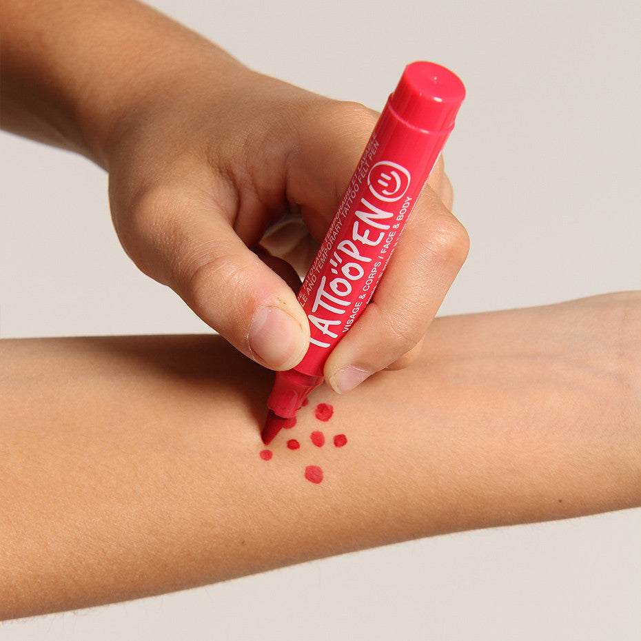 Hand zet rode stippen op een onderarm met de tattoopen