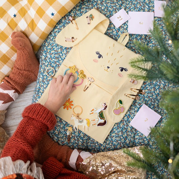Kind bekijkt accessoires op de open konijnenadventskalender, met genummerde zakjes ernaast.