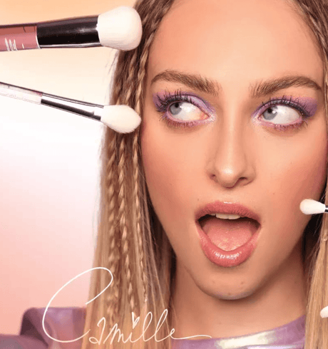 Camille met paarse oogmake-up en verschillende make-upkwasten rond haar gezicht, waaronder de Blusher Brush.