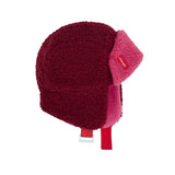 Cozy Tara chapka in bordeauxrood en roze met oorkleppen en verstelbare kinband, van opzij gezien.