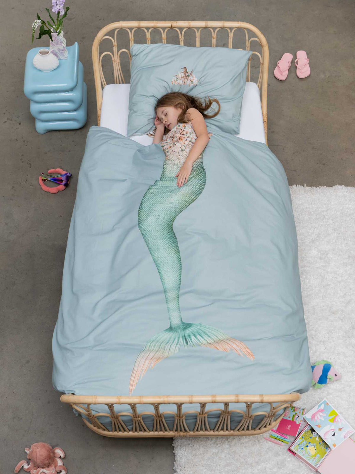 Kind onder het aqua dekbedovertrek Mermaid, met de zeemeerminprint als staart onder haar lichaam.