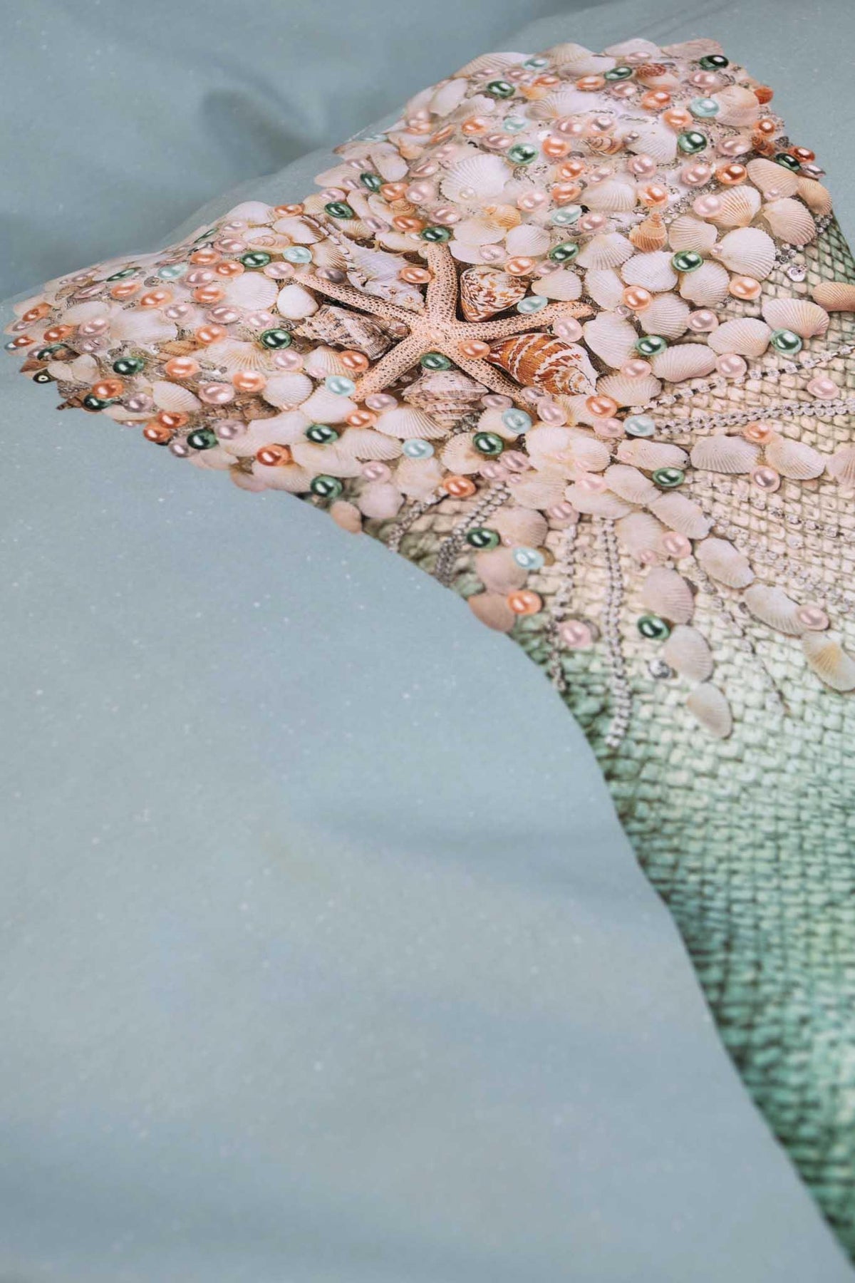 Detail van de zeemeerminprint op dekbedovertrek Mermaid, met schelpen, parels en een zeester op aqua.