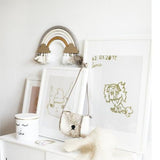 DIY regenboog Nude aan de muur boven een witte kast met ingelijste tekeningen en accessoires.