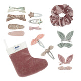 Roze fluwelen kerstsok met gouden sterren naast 14 haaraccessoires, waaronder een scrunchie en haarclips met strikjes.