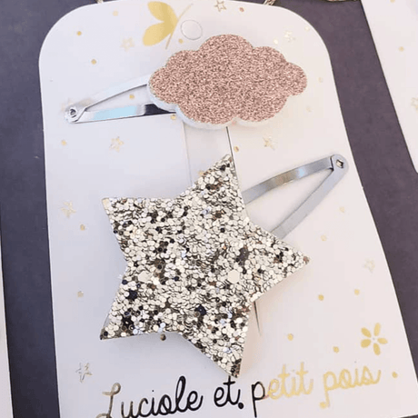 Detail van haarspelden met een goudkleurige glitterster en een rosékleurige glitterwolk op kliksluitingen.