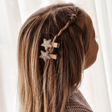 Twee haarspeldjes Glitter Star met goudkleurige glittersterren in het gedraaide haar van een kind.