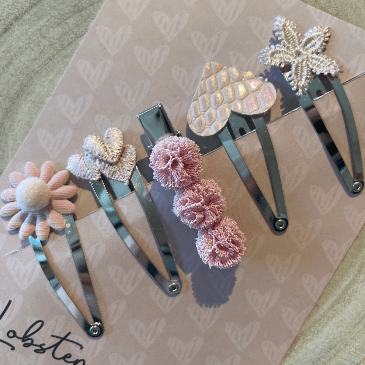 Vijf zilverkleurige haarspeldjes Pink Attitude met een roze bloem, hartjes, pompons en een glinsterende ster.