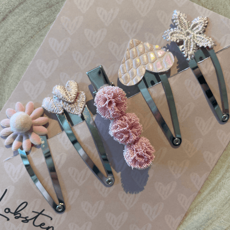 Vijf zilverkleurige haarspeldjes Pink Attitude met een roze bloem, hartjes, pompons en een glinsterende ster.