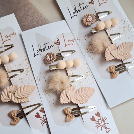 Drie sets Summer Vibes haarspeldjes op kaartjes, met roze bloemen, bolletjes, pluizige pompons, blaadjes en strikjes.