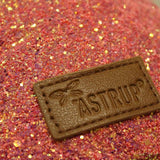 Detail van het roze glitterheuptasje met een bruin rechthoekig logolabel op de voorkant.