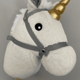 Detail van de witte kop van het Hoppy Horse Unicorn stokpaard met zwart oog, grijs halster en goudkleurige hoorn.