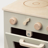 Detail van de beige houten speelkeuken met houten knoppen, kookpit en de ovendeur op een kier.
