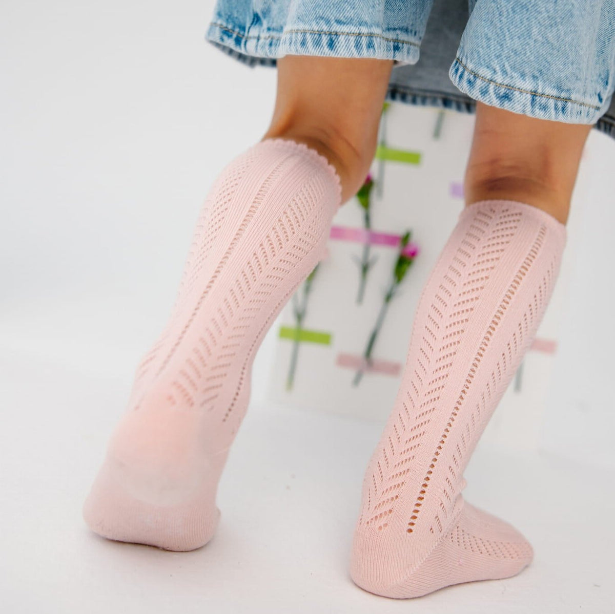 Lichtroze Lauren Pink kniekousen met opengewerkt patroon en golvende boord, gedragen onder een denimrok.