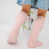 Lichtroze Lauren Pink kniekousen met opengewerkt patroon en golvende boord, gedragen onder een denimrok.
