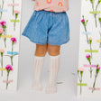Witte Toni kniekousen met opengewerkt patroon, gedragen met een blauwe short tussen bloemen.