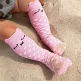 Roze Lilly a Pinky Kitty kniekousen met witte hartjes en kattengezichtjes, gedragen in het zand.