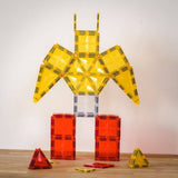 Robotfiguur van magnetische bouwblokken met gele armen en romp en rode benen op een houten tafel