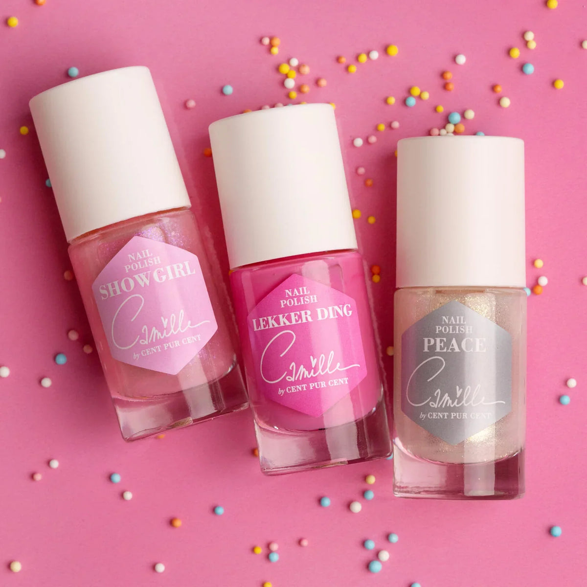 Camille nagellak in Show Girl, Lekker Ding en Peace op een roze achtergrond met gekleurde strooisels.