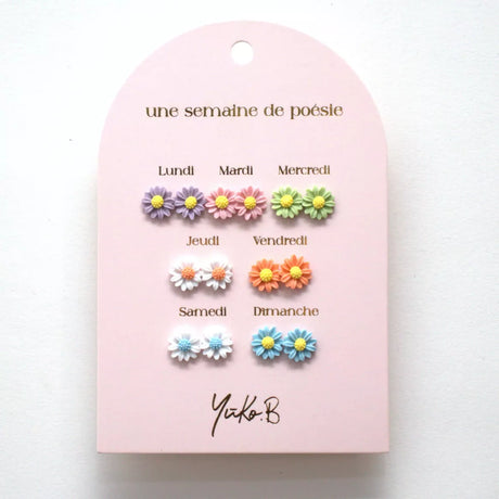 Zeven paar bloemoorbellen in paars, roze, groen, wit, oranje en blauw op een roze kaart.