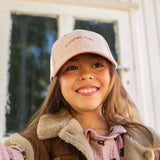 Glimlachend kind met een roze corduroy pet met het borduursel cosmic girl, van voren gezien.