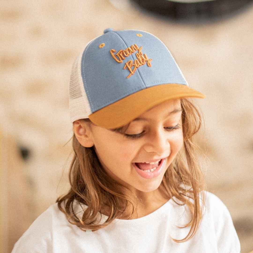 Kind draagt de pet Groovy Baby met muisgrijze voorkant, mosterdkleurige klep en ecru mesh.