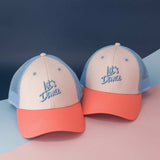 Twee Let's Dance-petten met ecru voorkant, blauw borduursel, koraalkleurige klep en lichtblauw gaas.