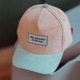 Close-up van de perzikkleurige Sweet Peach pet met mintgroene klep en het label ‘Cool kids only’.