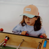 Kind met de perzikkleurige Hello Hossy Sweet Peach pet kijkt naar het tafelvoetbalspel.