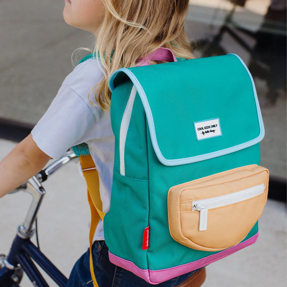 Kind op een fiets met de groene Hello Hossy Mini Ali rugzak met geel voorvak en roze accenten