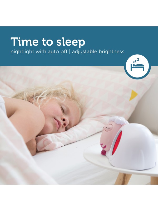 Slapend kind met roze slaaptrainer Sam op een tafeltje naast het bed, met gesloten ogen en rood scherm.