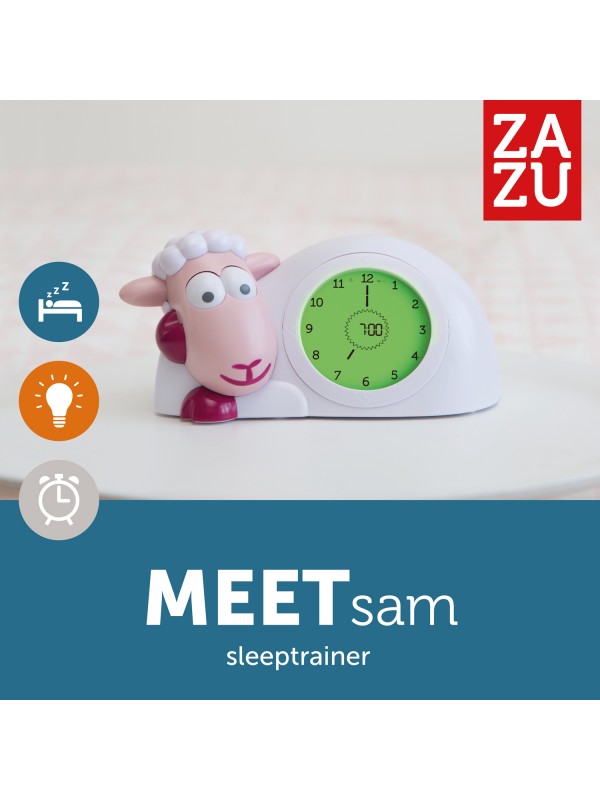 Roze Zazu slaaptrainer Sam met open ogen en groene wijzerplaat op een wit tafeltje.