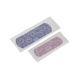 Een paarse en een roze Smiley World glitterpleister met witte smileys, elk op een beschermvel.