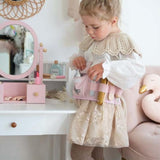 Kind draagt de roze kappersspeelset om het middel en speelt naast een kaptafel met spiegel.