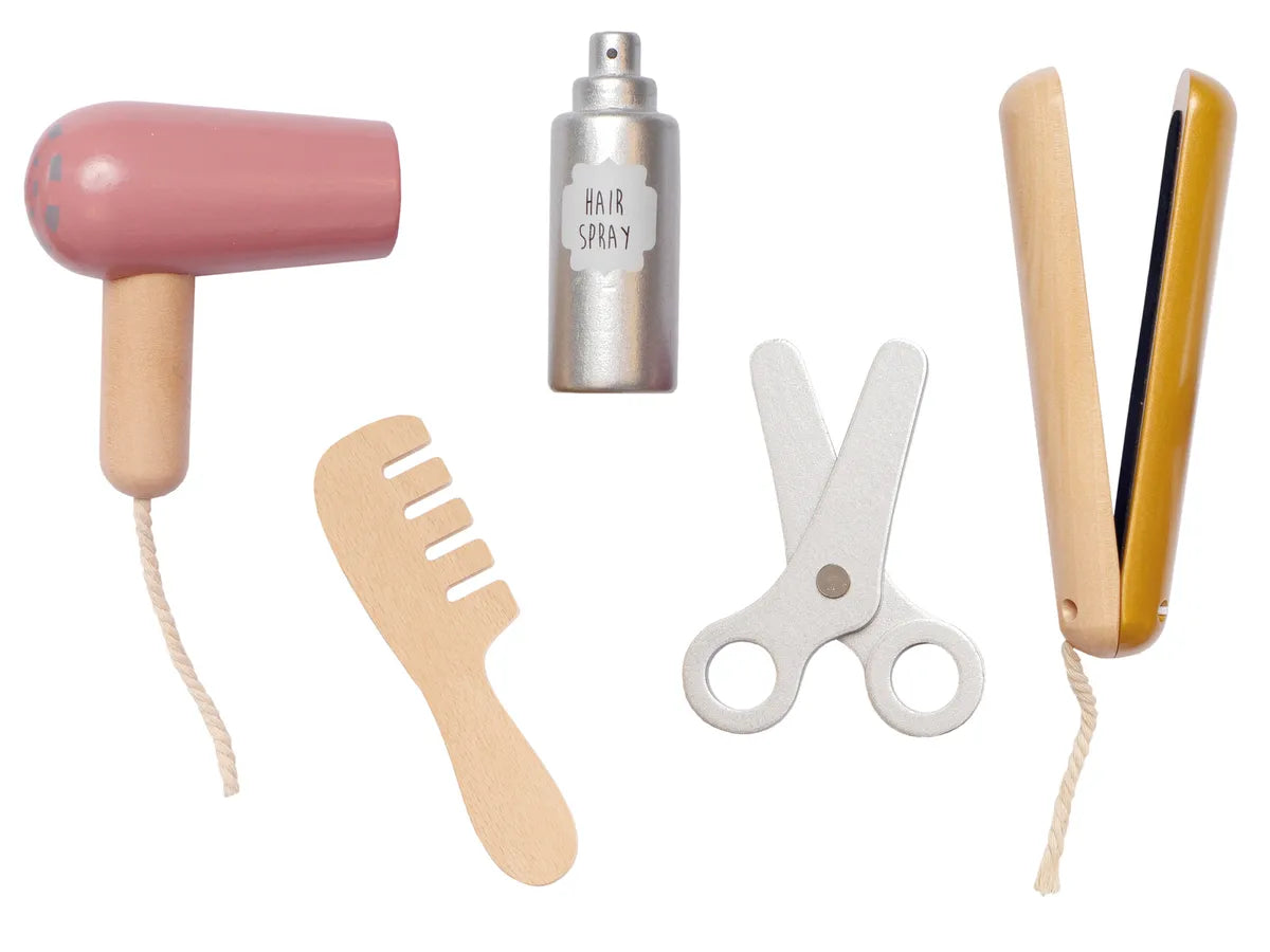 Houten kappersspeelgoed los uitgestald: roze föhn, flesje haarlak, kam, schaar en stijltang.