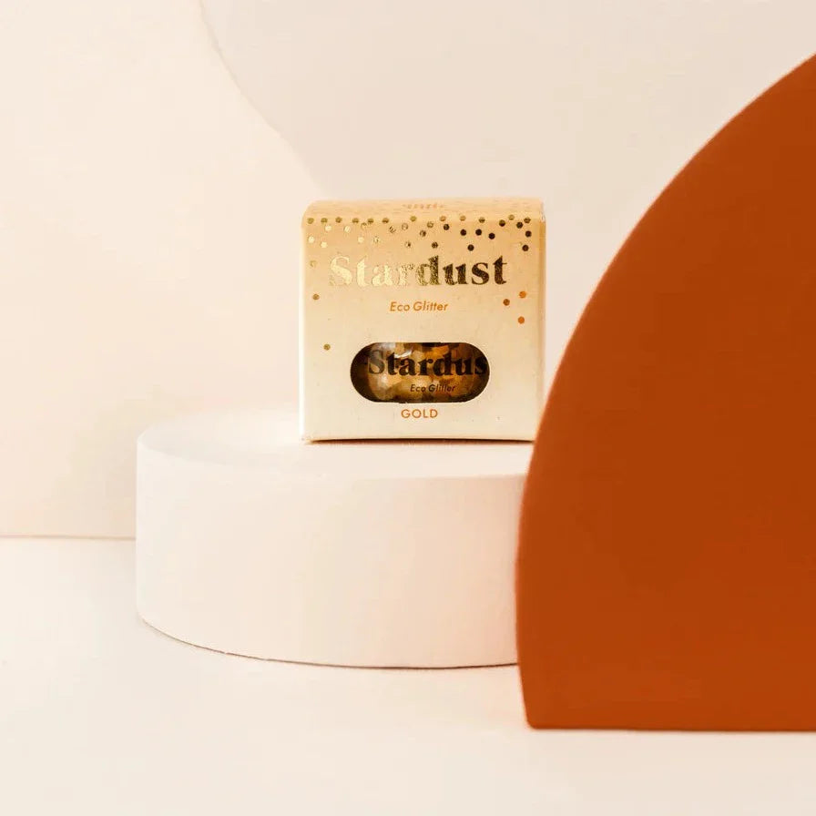 Star Dust Gold gezichtsglitter in een goudkleurig doosje met kijkvenster op een witte sokkel.