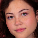 Model met glanzende roze oogschaduw en paarse eyeliner, met de Stardust Topper Camille op de oogleden.