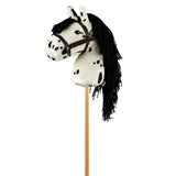 Wit stokpaardje met zwarte stippen, lange zwarte manen en een bruin hoofdstel, van opzij gezien.