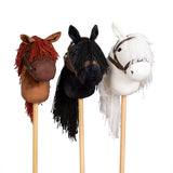 Drie stokpaardjes naast elkaar: bruin met roodbruine manen, zwart met zwarte manen en wit met witte manen.
