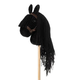 Zwart stokpaardje met lange zwarte manen en een bruin hoofdstel, schuin van opzij gezien.