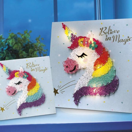 Twee string art schilderijtjes met een witte eenhoorn, regenboogkleurige manen en de tekst ‘Believe in Magic’.