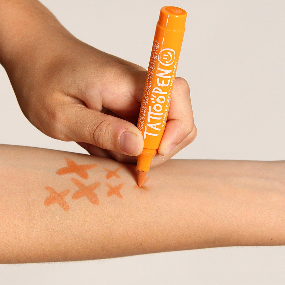 Hand tekent oranje kruisjes op een onderarm met de oranje tattoopen