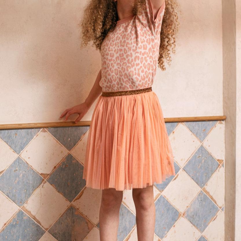 Meisje draagt de roze tule rok Dawn Pink met glittertailleband en een shirt met luipaardprint bij een tegelwand.
