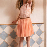Meisje draagt de roze tule rok Dawn Pink met glittertailleband en een shirt met luipaardprint bij een tegelwand.