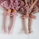 Twee kinderen met roze en lichtgekleurde tutu kniekousen met ruches, onder bijpassende rokken.
