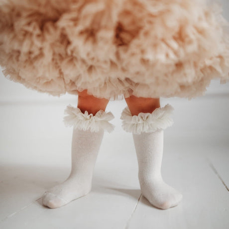 Ecru tutu kniekousen met ruches, gedragen onder een beige rok met ruches.